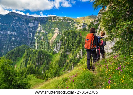 Woman\'s hiking team with colorful backpacks walking on narrow trail,Bucegi mountains,Carpathians,Transylvania,Romania,Europe