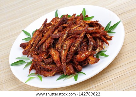 side view of Anchovy fish fry with curry leaves,Anchovies serves as a excellent source of calcium, proteins, vitamins, and omega-3 fatty acids,