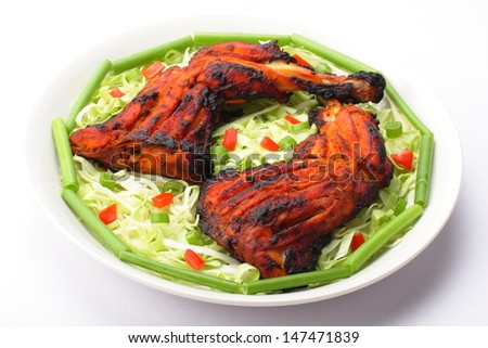 Tandoori chicken on plate with fresh vegetables.