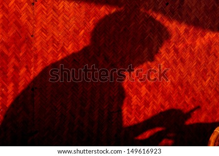 A cell phone texting person\'s shadow  behind textured wall