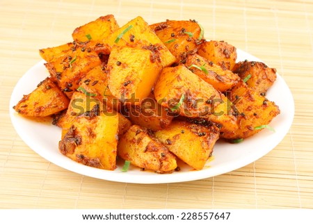 Spicy fried potatoes with herbs and spices served in white plate. Shallow depth of field photograph