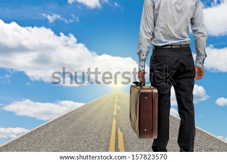 Businessman going to the future with suitcase on sunny day