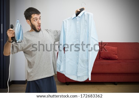 A single man in pyjamas scared about ironing his shirt