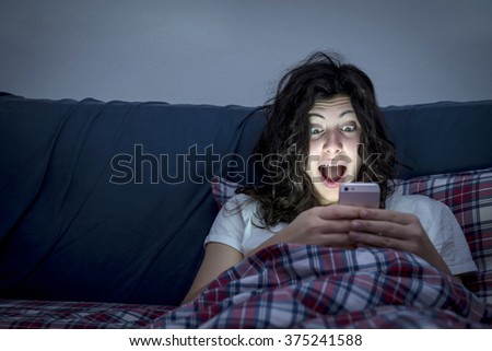 Surprised girl using smartphone in bed