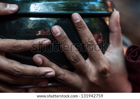 Detail of monk\'s hands holding a begging bowl in Amarapura near Mandalay in Myanmar