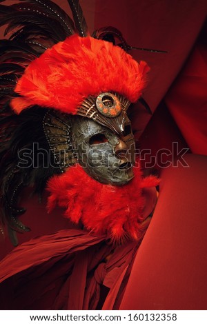 Decorative mask with red and black feathers on a red background