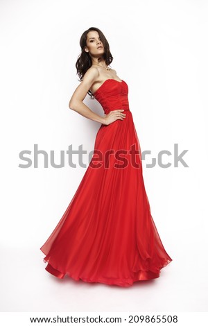 Portrait of a beautiful brunette model in red,long dress posing in studio