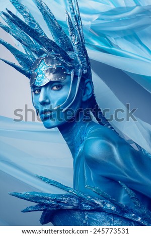 Portrait of painted woman in original head wear on blue background