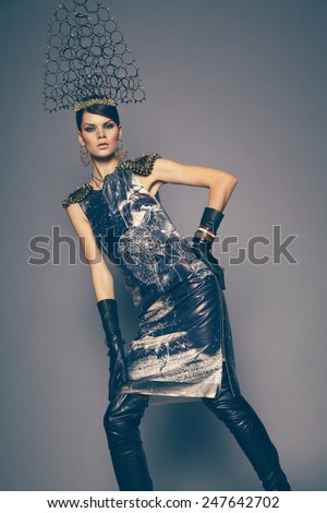 Gorgeous brunette woman in dress and head wear with spikes and circles against dark background