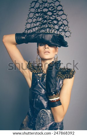 Gorgeous brunette woman in dress and head wear with spikes and circles against dark background
