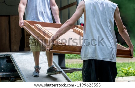 strong young men moving furniture into a moving van