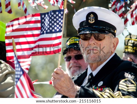 St Joseph Michigan May 2, 2014: A retired naval officer waves an american flag, as he rides in the Blossom time parade in Michigan USA