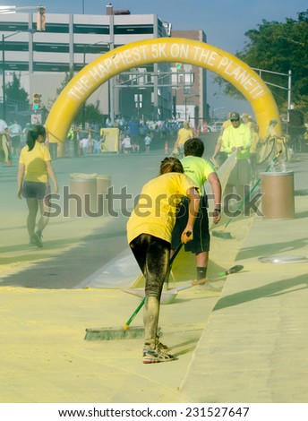 Indiana, South Band - September 26, 2014:  volunteers coated in yellow, clean up south bend streets of all the extra powder that was use to cover runners in, during the south bend color run  5k race