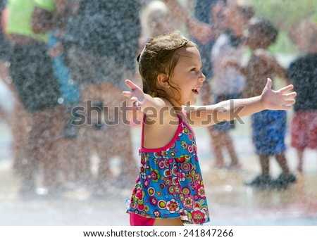 A laughing little girl dances happily in a summer fountain in Michigan. welcome summer!