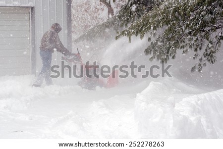 A man works to clear a sidewalk in deep white snow