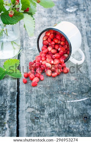 Bouquet of wild strawberries on a rural texture. glass were scattered berries . there is a place for inscriptions .