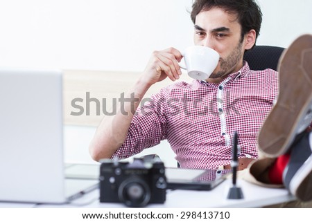 freelancer at work. happy man drinking coffee and looking at a computer. morning designer