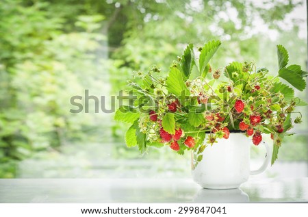 strawberry bouquet on a window sill . summer picture . first summer berries . the lights of a sun. toned photo . close-up