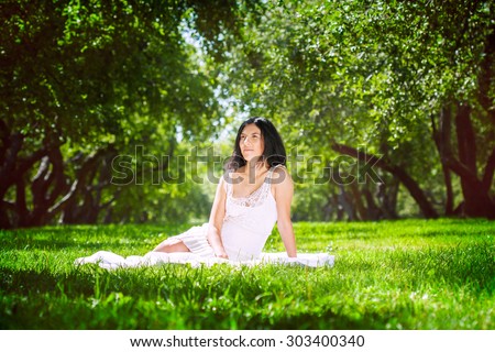 happy girl sitting on the grass in the park . happiness and tranquility . sunny summer . summer vacation in the park