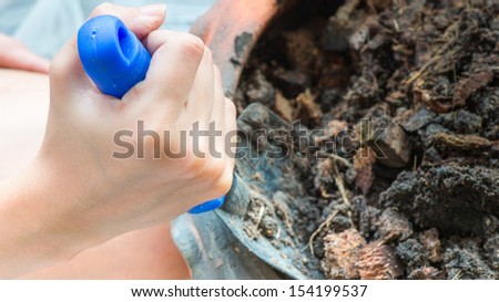 Planting trees at home, Woman\'s hand holding a spade into the ground.