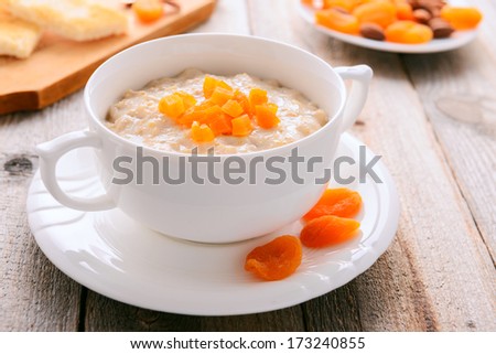 Oatmeal porridge with dried apricots in white bowl
