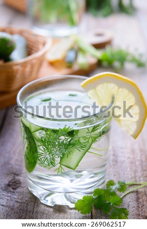A glass of  cucumber water with dill decorated with lemon slice