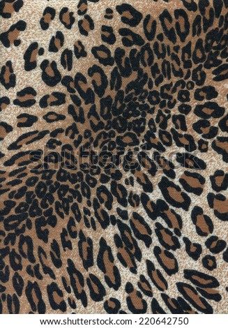 The pattern on the fabric in the form of leopard skins. Black spots on a light brown background.