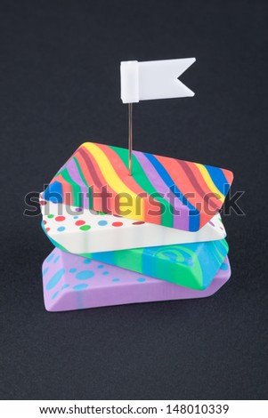 Four colored eraser with white flag on the black background