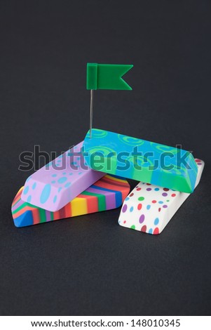 Four colored eraser with green flag on the black background