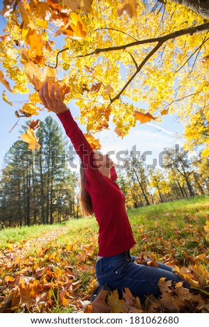 Young smiling girl throws autumn maple leaves