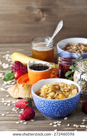 Healthy breakfast including flakes, muesli, honey, berries, jam and coffee