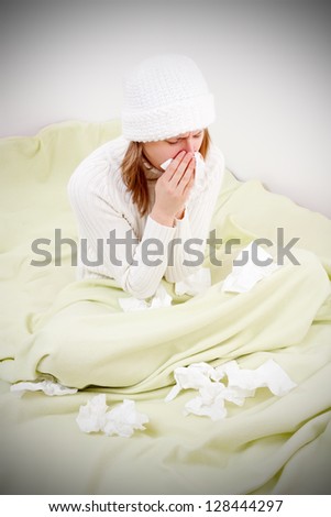 Sick girl staying in bed suffering from influenza and blowing her nose.