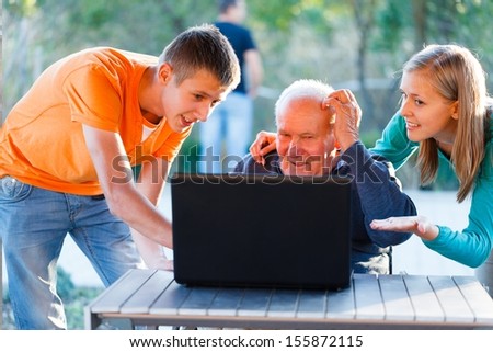 Grandchildren helping out grandfather with using a laptop.