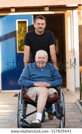 Old father being pushed in his wheelchair by his son.