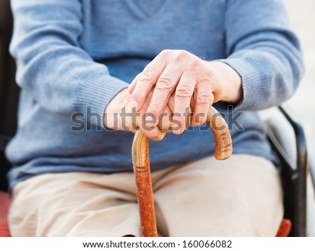 Closeup of an old man\'s hand holding his stick.