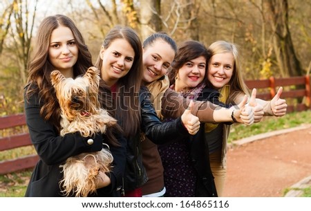 Huge group of women showing thumbs up for a cute little pet dog.