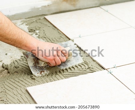 Bathroom floor tiling by manual worker.