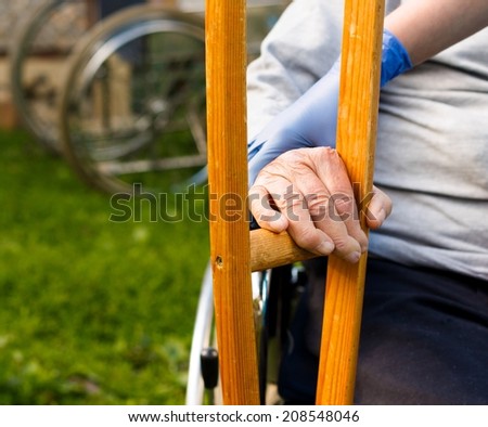 Elderly homecare - nurse handing crutch to sick patient.