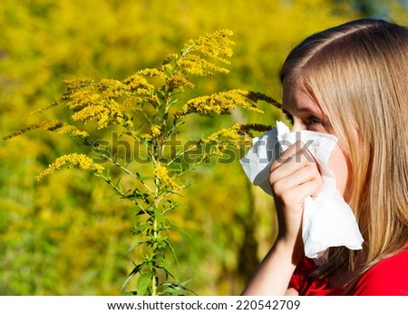 Young woman blowing nose in handkerchief because of allergy.
