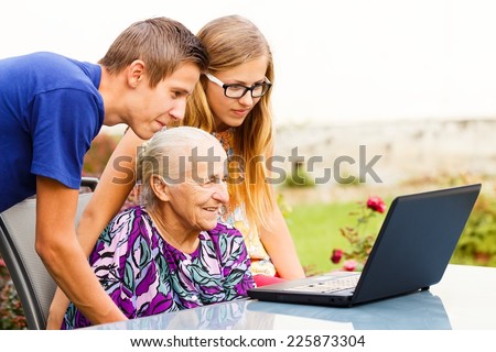 Loving grandchildren teaching their grandmother how to use a computer.