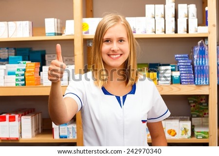 Kind young pharmacist showing confident thumbs up.