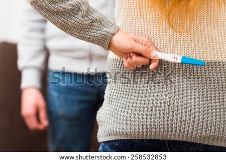 Close-up of a woman holding positive pregnancy test, waiting to surprise her lover.