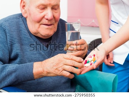 Senile elderly man taking daily medicine at the nursing home.