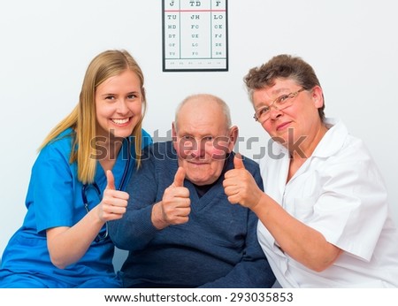 Happy moments at the nursing home, elderly man showing thumbs up with his caregivers.