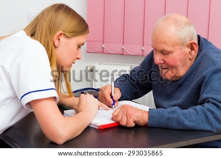 Elderly man signing medical papers at the doctor\'s office.