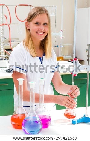 Young scientist making acid base titration in well equipped laboratory.
