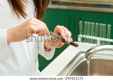 Technician washing used laboratory vessels after experiments.