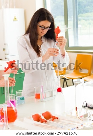 Devoted young researcher working on experiment, measuring with pipette colourful liquid substances.