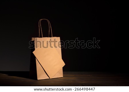 Luxury classic shopping bag and envelope made of craft paper presented on aged wood