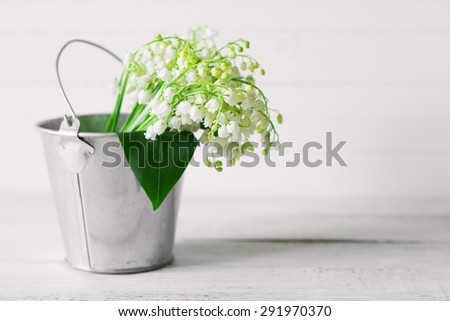 Bouquet of lilies of the valley, wild flowers in a metal bucket on wood background